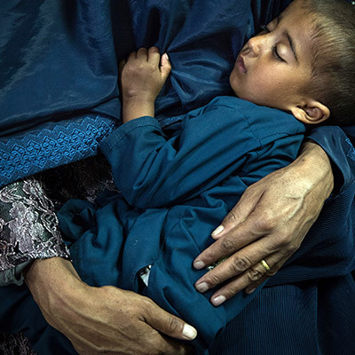 Enfant afghan endormi dans les bras de sa mère à l'IMFE de Kaboul