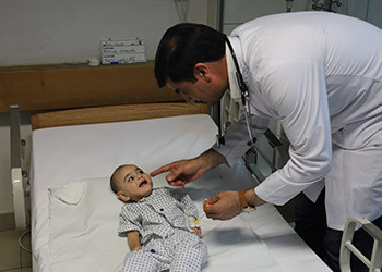 Un médecin afghan nourrit un enfant malnutri avec un sachet thérapeutique